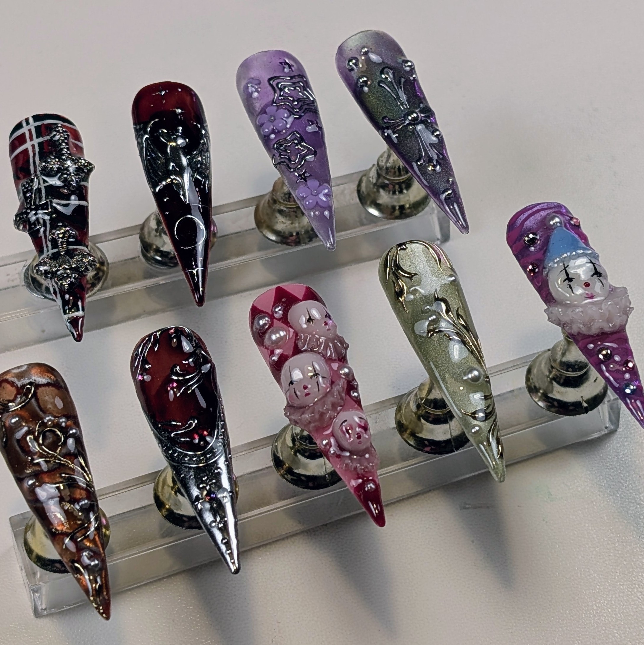 Auswahl verschiedener Press-On-Sets auf Display-Stäben — Gothic, Clown, lila Florals, Tartan, Chrome